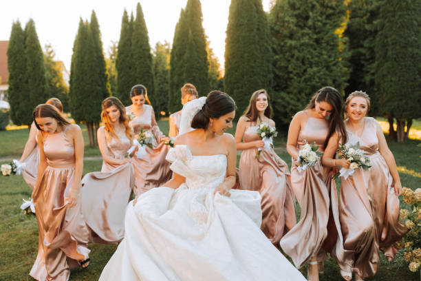 Beautiful elegant slim smiling bridesmaids in delicate pink beige summer dress on the wedding ceremony.